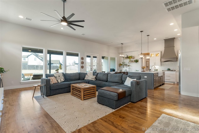 living area with ceiling fan with notable chandelier, recessed lighting, visible vents, and wood finished floors