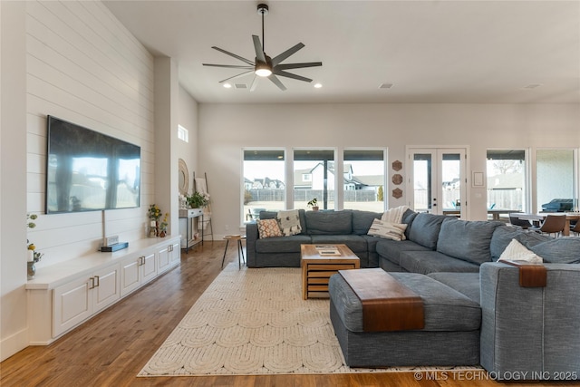 living area featuring recessed lighting, plenty of natural light, wood finished floors, and french doors