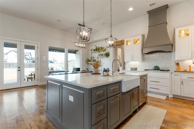 kitchen with gray cabinets, custom range hood, visible vents, decorative backsplash, and white cabinets