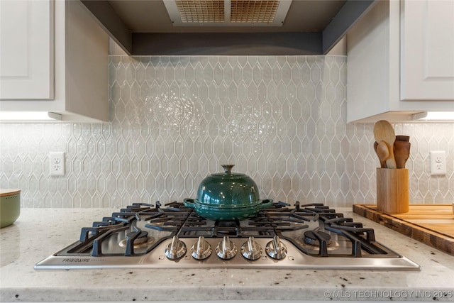 details featuring light stone counters, white cabinetry, stainless steel gas stovetop, and decorative backsplash