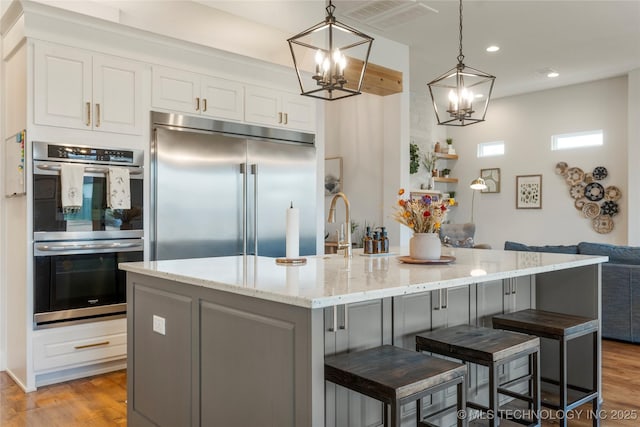 kitchen with stainless steel appliances, visible vents, light wood-style floors, and white cabinetry