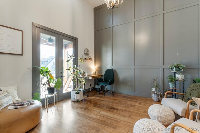 sitting room with a towering ceiling, light wood finished floors, and a decorative wall