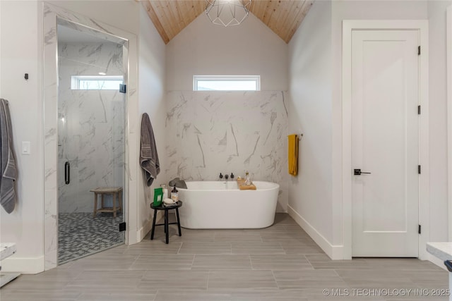 full bath with a wealth of natural light, a freestanding bath, lofted ceiling, and a marble finish shower