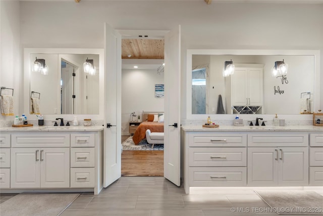 full bath featuring a sink, two vanities, and ensuite bathroom