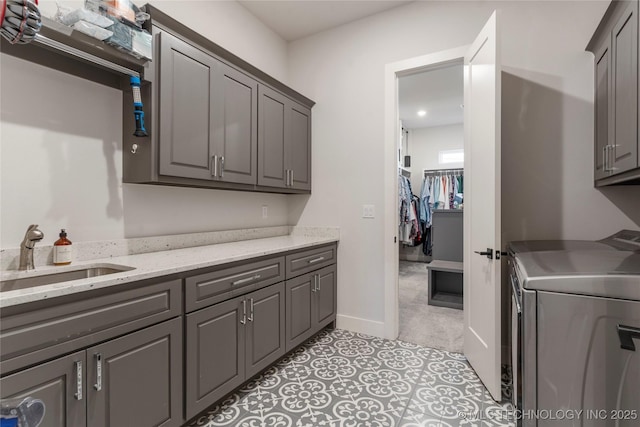 laundry area with a sink, washer / dryer, baseboards, and cabinet space