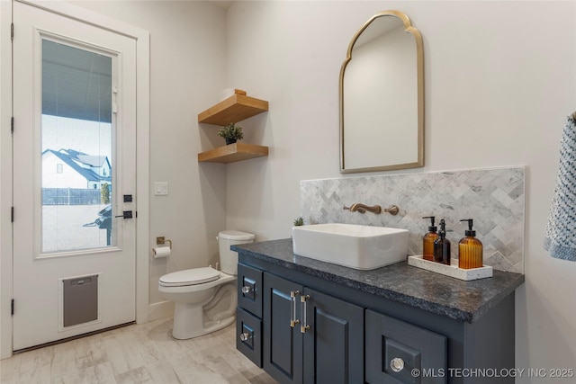 bathroom featuring toilet, vanity, decorative backsplash, and wood finished floors