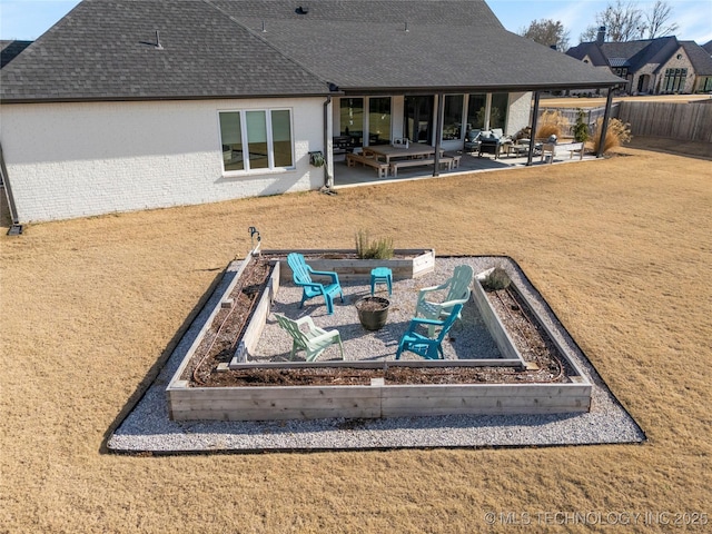 rear view of property featuring a garden, a lawn, a patio, roof with shingles, and fence