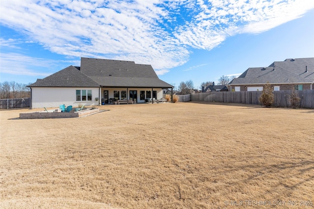 rear view of house with a patio, a yard, and a fenced backyard