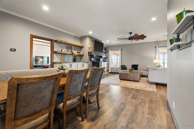 dining space featuring recessed lighting, dark wood-type flooring, a fireplace, a ceiling fan, and ornamental molding