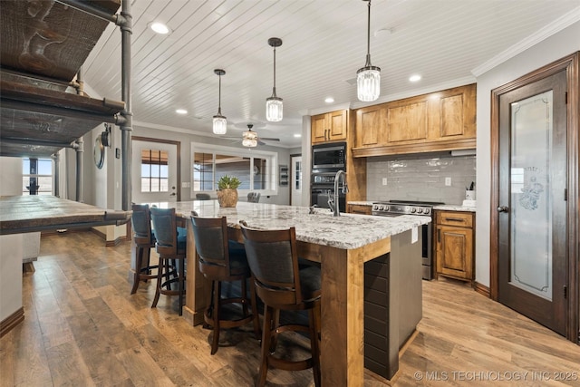 kitchen with appliances with stainless steel finishes, light wood-type flooring, backsplash, and crown molding