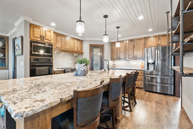 kitchen with stainless steel appliances, light wood-style floors, brown cabinetry, and crown molding