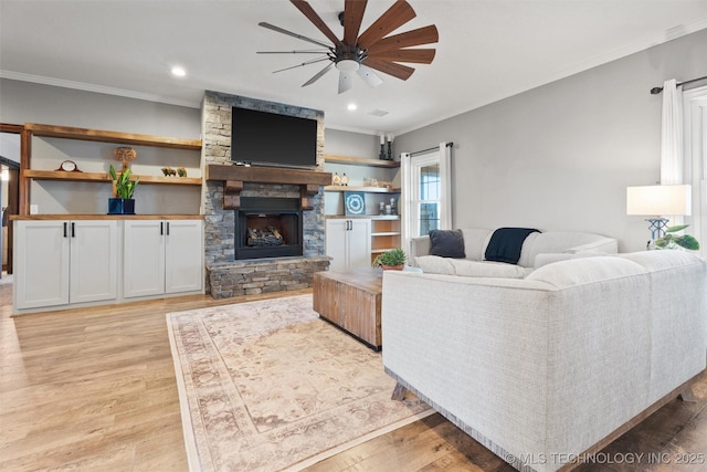 living room with a fireplace, crown molding, light wood finished floors, and ceiling fan