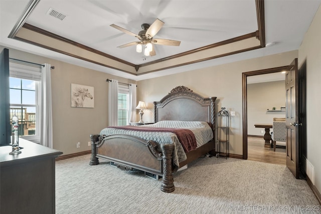 bedroom featuring baseboards, visible vents, a raised ceiling, and ornamental molding