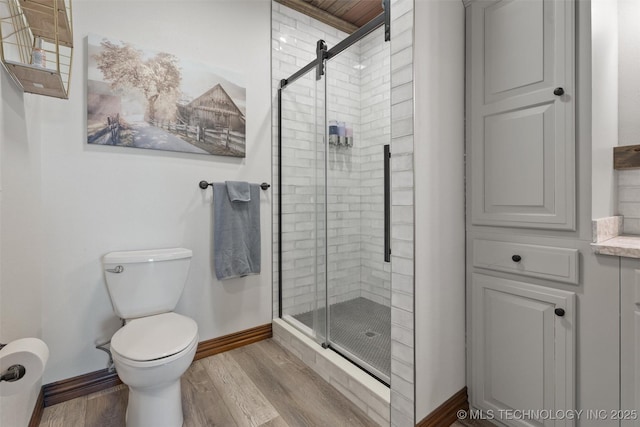 bathroom with toilet, a shower stall, baseboards, and wood finished floors