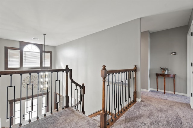 corridor with visible vents, carpet floors, an upstairs landing, and baseboards