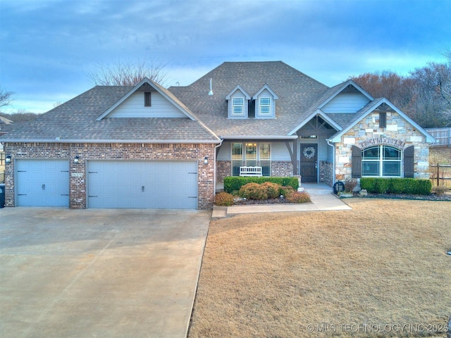 craftsman inspired home featuring a garage, concrete driveway, roof with shingles, a front yard, and brick siding