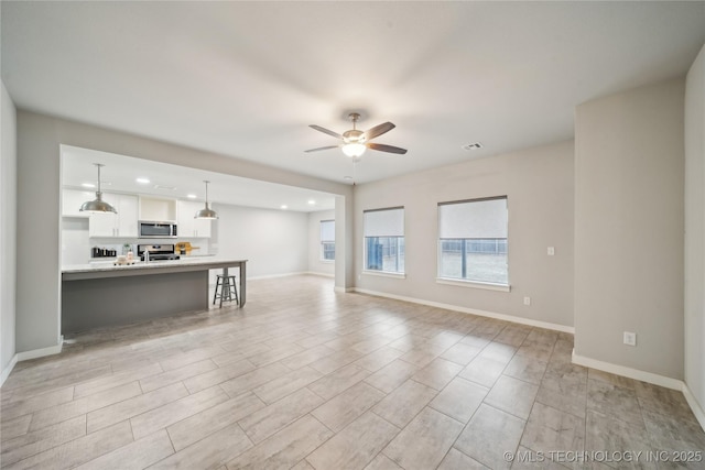 unfurnished living room with ceiling fan, recessed lighting, visible vents, and baseboards