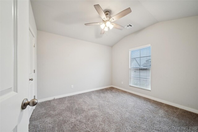 carpeted spare room with vaulted ceiling, ceiling fan, visible vents, and baseboards