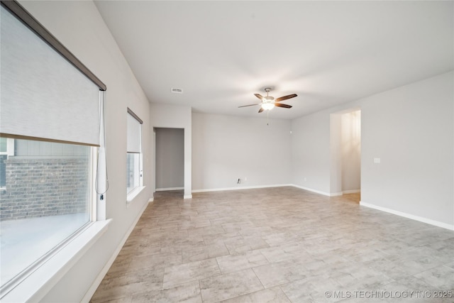 unfurnished room featuring a ceiling fan, visible vents, and baseboards