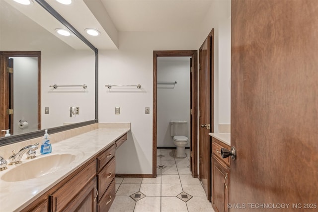 bathroom with toilet, vanity, baseboards, and tile patterned floors