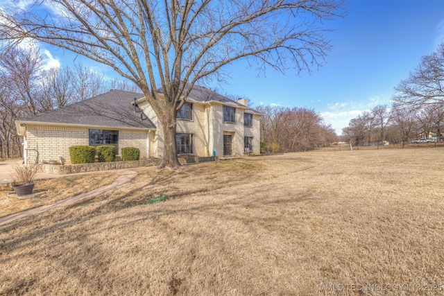 view of front of property with brick siding, fence, a chimney, and a front lawn