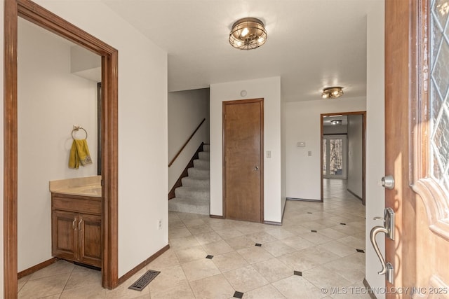 entrance foyer featuring light tile patterned floors, stairway, visible vents, and baseboards