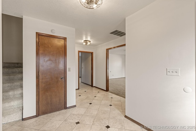 hall with stairway, baseboards, visible vents, and light colored carpet