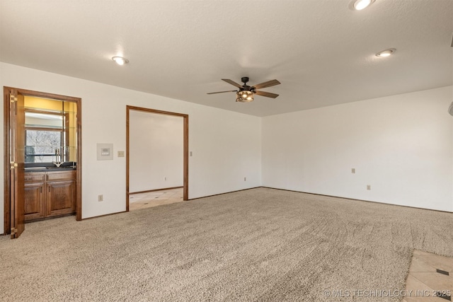 empty room featuring a textured ceiling, a ceiling fan, and light colored carpet