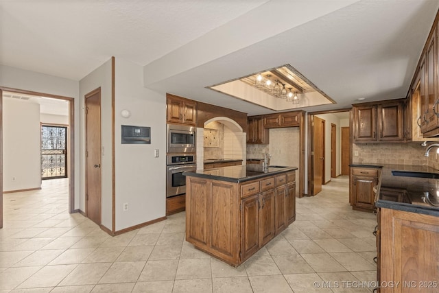 kitchen featuring stainless steel appliances, dark countertops, a sink, and light tile patterned flooring