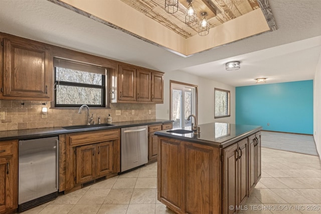 kitchen with dark countertops, a sink, stainless steel dishwasher, and light tile patterned floors