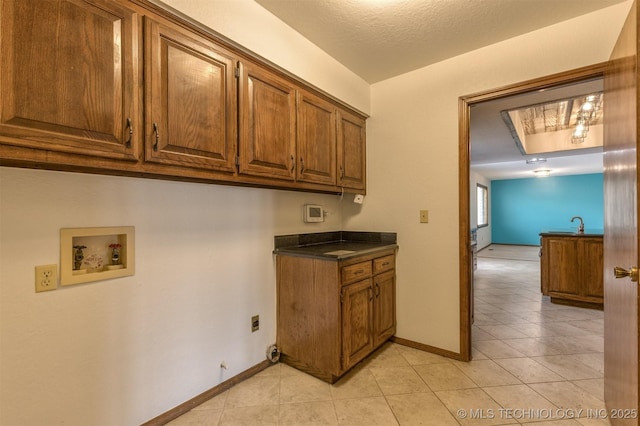 kitchen with light tile patterned floors, brown cabinetry, and baseboards