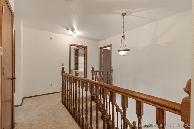 corridor with baseboards, light colored carpet, and an upstairs landing