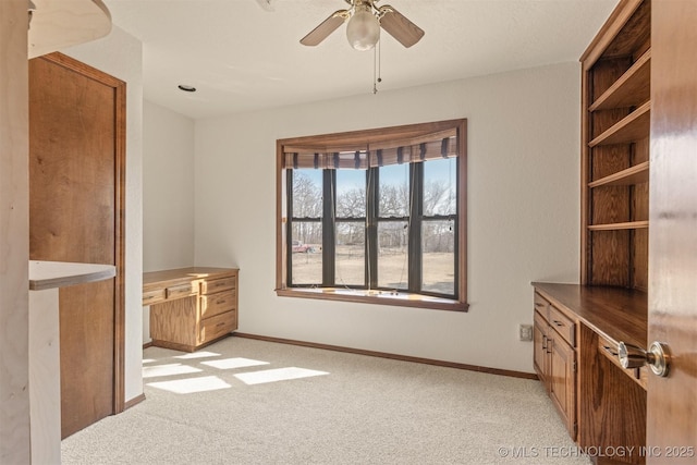 office space featuring ceiling fan, baseboards, and light colored carpet