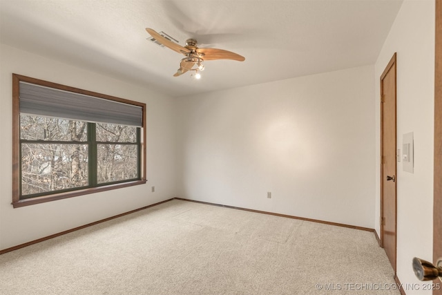 empty room with baseboards, a ceiling fan, and light colored carpet