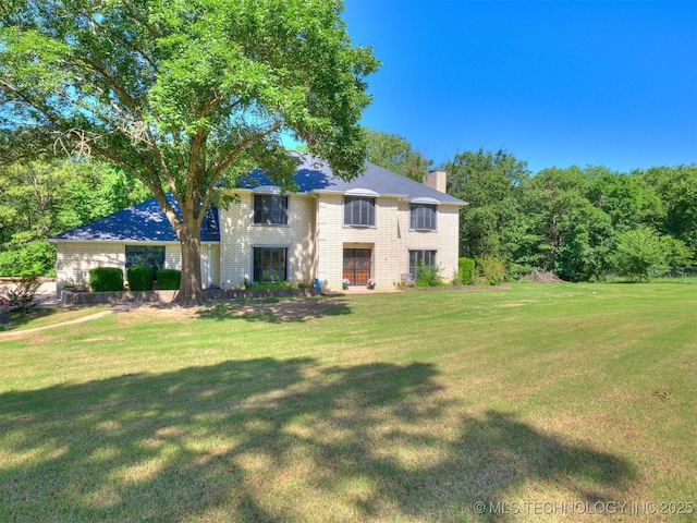 8934 S 41st W Ave, Tulsa, OK 74132 - view of front facade with a chimney, a front lawn, and brick siding