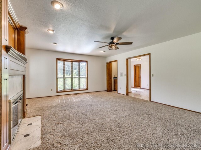 8934 S 41st W Ave, Tulsa, OK 74132 - unfurnished living room featuring light colored carpet, a ceiling fan, a fireplace with flush hearth, and a textured ceiling