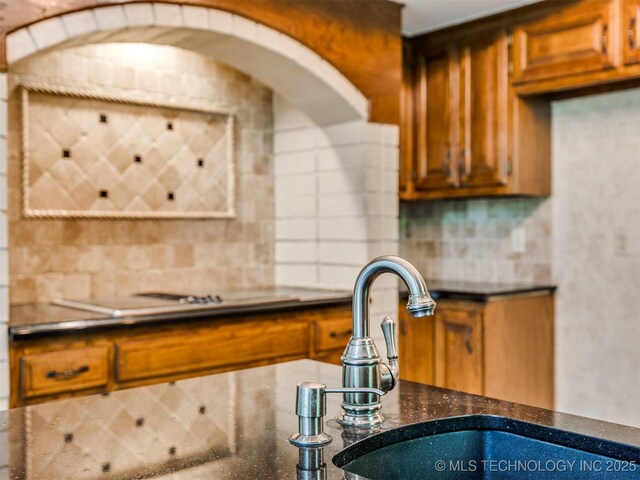 8934 S 41st W Ave, Tulsa, OK 74132 - kitchen featuring decorative backsplash, brown cabinetry, and dark stone counters