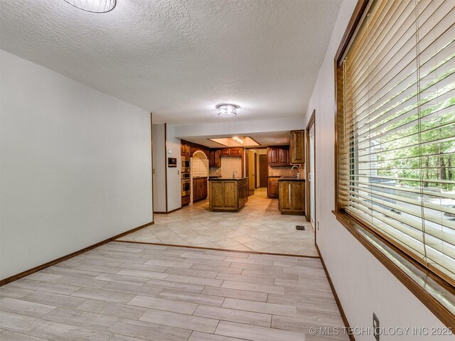 8934 S 41st W Ave, Tulsa, OK 74132 - kitchen with brown cabinetry, a center island, dark countertops, a textured ceiling, and oven
