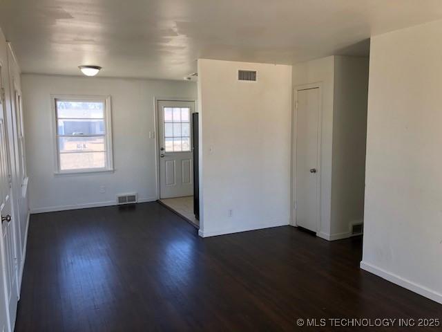 interior space with dark wood-style floors, visible vents, and baseboards