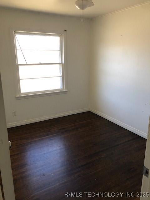 empty room with baseboards, dark wood finished floors, and a healthy amount of sunlight