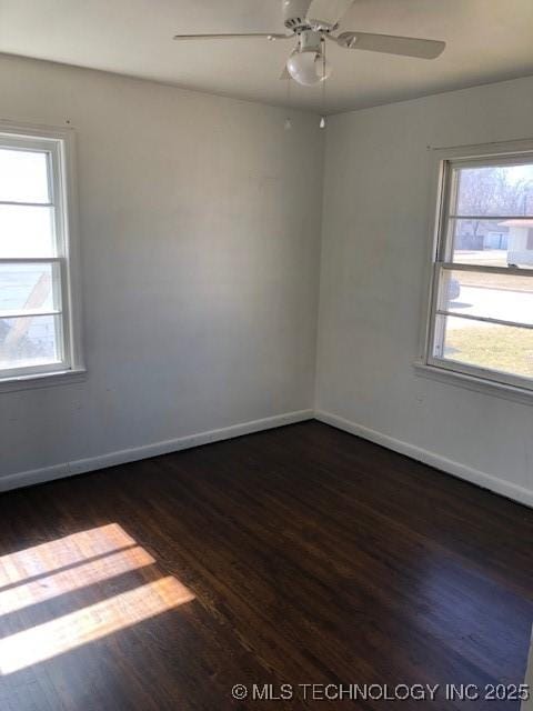 empty room with dark wood-style floors, a ceiling fan, and baseboards