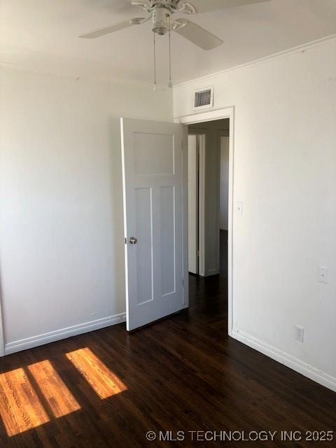 empty room with visible vents, baseboards, ceiling fan, and dark wood-type flooring