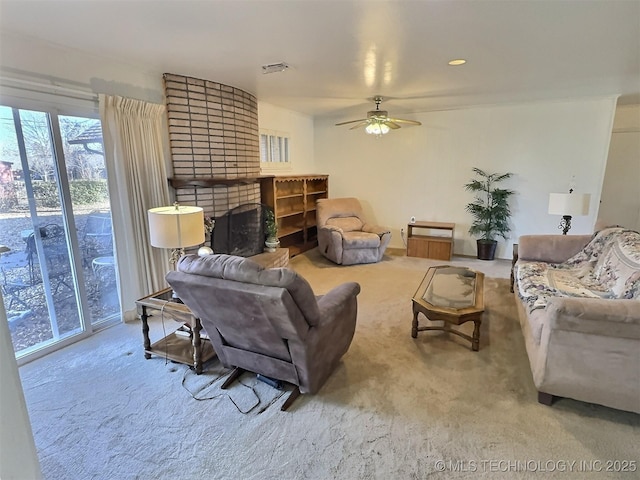 carpeted living area with a fireplace, visible vents, and a ceiling fan