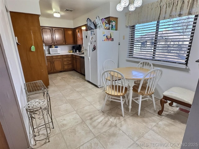 kitchen featuring brown cabinets, light countertops, visible vents, a sink, and white appliances