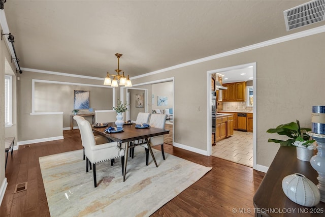 dining space with ornamental molding, wood finished floors, and visible vents