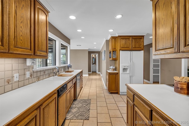 kitchen with a sink, light countertops, backsplash, brown cabinets, and white fridge with ice dispenser