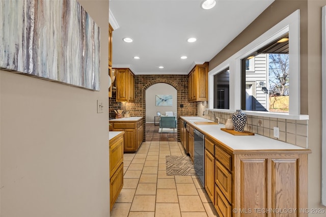 kitchen featuring light tile patterned floors, arched walkways, dishwasher, light countertops, and backsplash