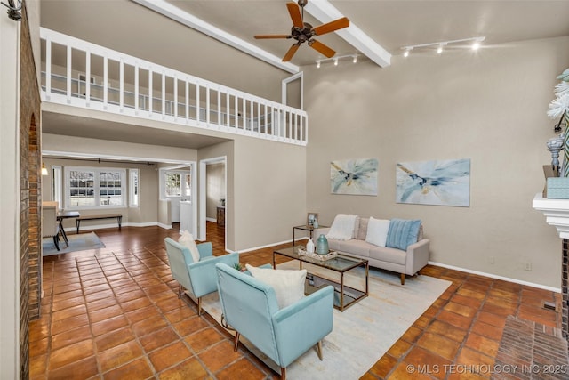 tiled living area featuring rail lighting, a towering ceiling, a ceiling fan, beamed ceiling, and baseboards