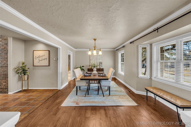 dining space with a notable chandelier, crown molding, a textured ceiling, and wood finished floors