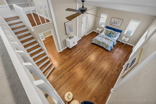 living area featuring baseboards, stairway, ceiling fan, and wood finished floors